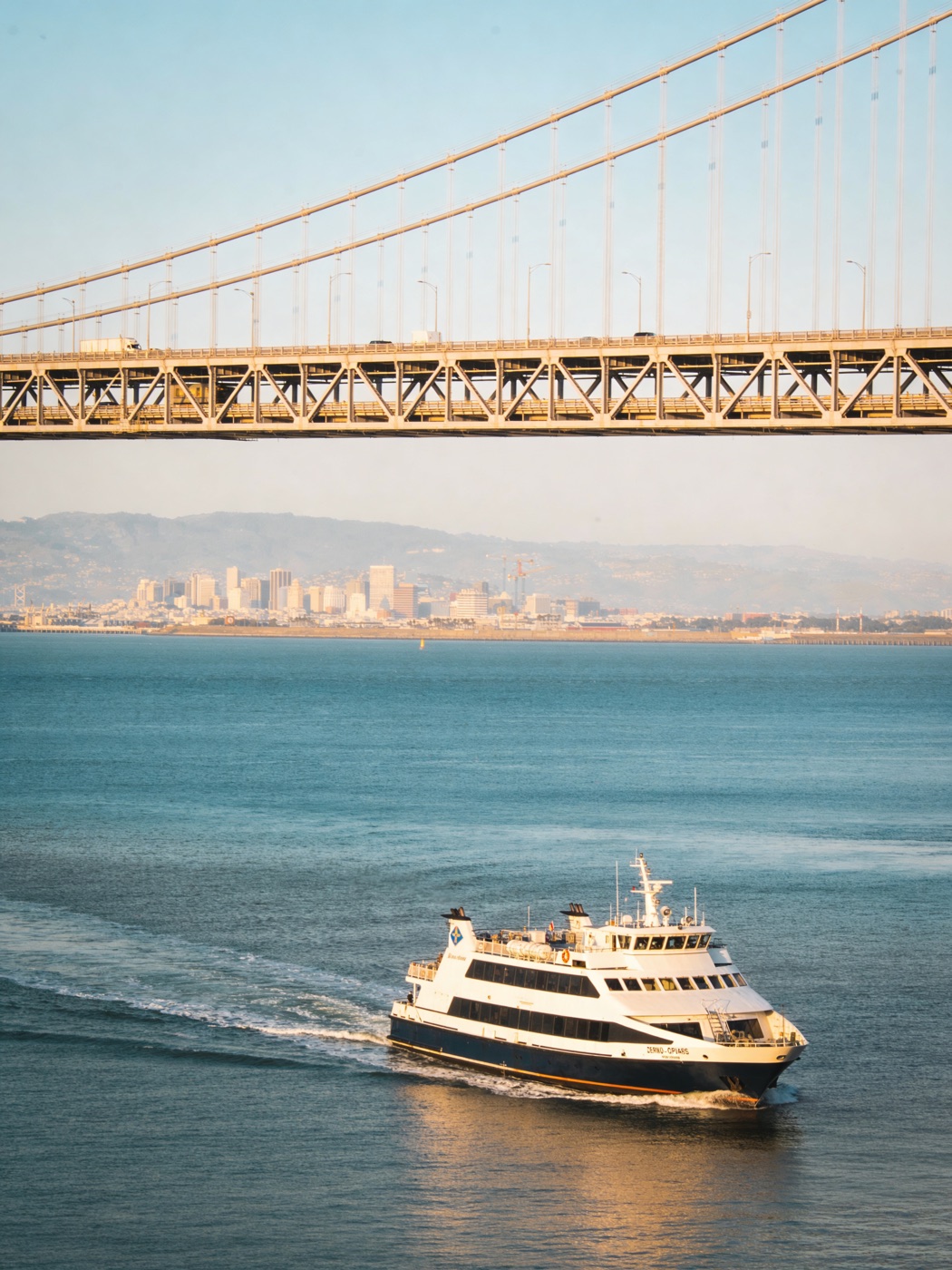 A commercial passenger ferry crossing San Francisco Bay beneath the Bay Bridge